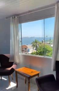 een woonkamer met een tafel en een groot raam bij Pousada Alto da Maroca in São Francisco do Sul