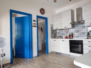una cocina con armarios blancos y una puerta azul en Beach House, en Platamona