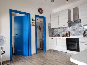 a kitchen with white cabinets and a blue door at Beach House in Platamona +25 photos