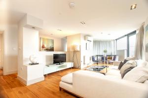 a living room with a white couch and a tv at Modern City Apartments in London