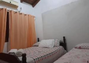 sypialnia z 2 łóżkami i pomarańczową zasłoną w obiekcie Pousada Claudia e Juliano w mieście São Gabriel
