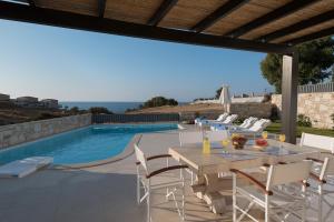 a patio with a table and chairs next to a swimming pool at Lygaries Villas in Panormos Rethymno