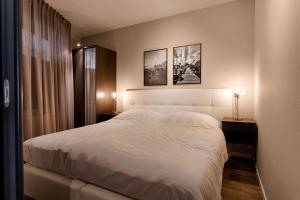 1 dormitorio con 1 cama blanca grande y 2 lámparas en Zuiderzeestate 35, prachtig appartement aan het IJsselmeer, en Makkum