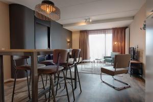 een woonkamer met een bar en stoelen in een kamer bij Zuiderzeestate 35, prachtig appartement aan het IJsselmeer in Makkum