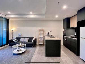 cocina y sala de estar con sofá y mesa en Brand New Stylish 1BR Apartment, Specious Space, Free Parking, Self Check-in en Canberra