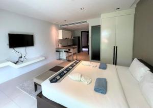 uma sala de estar com uma grande cama branca e uma televisão em Private apartment at Emerald Terrace em Praia de Patong