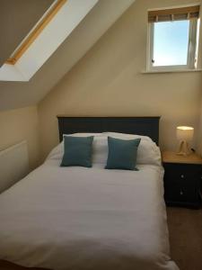 a bedroom with a white bed with two blue pillows at Roomy Penthouse 2 double bed apartment - Spacious - Central Beeston - Free secure parking - in Nottingham