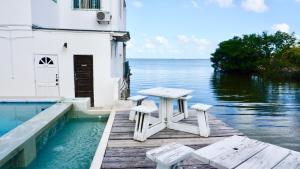 une table et des bancs assis sur un quai à côté de l'eau dans l'établissement See Belize SUNRISE Sea View Studio with Infinity Pool & Overwater Deck, à Belize City