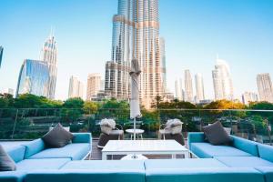 a rooftop patio with blue couches and a city skyline at THE CLOSEST building to Burj Khalifa with Fountain View in Address Opera Residence in Dubai