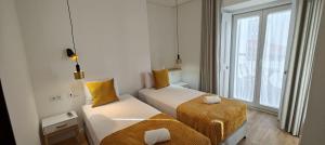a small room with two beds and a window at Correio Velho Suites in Lisbon