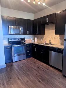 een keuken met zwarte kasten en roestvrijstalen apparatuur bij Comfortable Apartment in Dallas in Addison