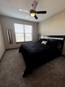 a bedroom with a black bed and a ceiling fan at Comfortable Apartment in Dallas in Addison
