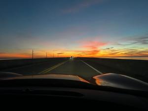 un'auto che guida lungo l'autostrada al tramonto di Studio Black Castle RV a Miami