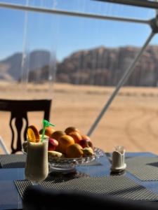 a plate of fruit on a table with a view of the desert at Wadi rum anwar luxury camp in Wadi Rum