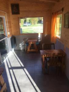 Zimmer mit einem Tisch und einem Fenster in einer Hütte in der Unterkunft Carelhue in Epuyén
