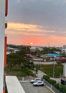 um pôr-do-sol sobre um parque de estacionamento com carros estacionados em Cozy Apartment with pool em Montería