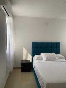 a bed with a blue headboard in a bedroom at Cozy Apartment with pool in Montería