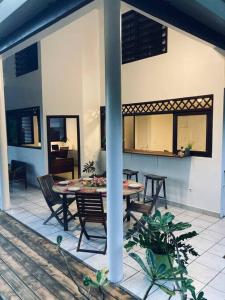 eine Terrasse mit einem Tisch und Stühlen in einem Haus in der Unterkunft Fare Manu Ura, Maison Tropicale accueillante in Paea
