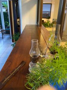 una mesa de madera con dos jarrones de cristal y plantas. en Fare Manu Ura, Maison Tropicale accueillante, en Paea