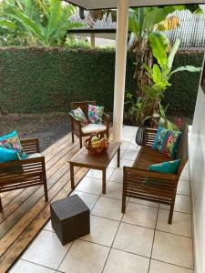 une terrasse avec des chaises et une table avec un bol de fruits dans l'établissement Fare Manu Ura, Maison Tropicale accueillante, à Paea