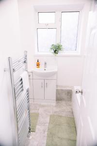 a white bathroom with a sink and a window at 6 bedroom property in Sidcup