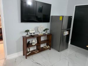 a kitchen with a refrigerator and a table with a tv at Seaside Escape in Wickhams