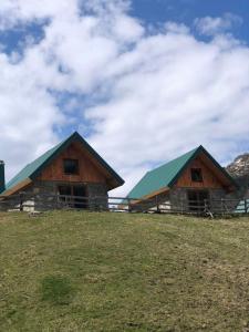 two wooden buildings with green roofs on a field at Vikendice Suvo Do in Berane