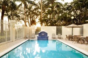 a swimming pool with a table and chairs at TownePlace Suites Boca Raton in Boca Raton