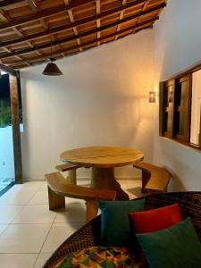 uma sala de jantar com uma mesa de madeira e um sofá em Casa de praia Enseadas do corais - 20 metros da praia em Cabo de Santo Agostinho