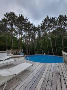 una terraza de madera con sillas y una piscina azul en Suite-appartement 2 chambres à la campagne. Rez de jardin, en Dunham