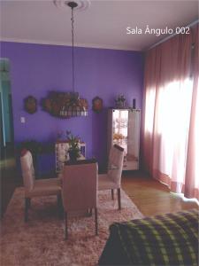 a dining room with purple walls and a table and chairs at Quarto Carnaval 2024 Salvador in Salvador