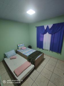 een slaapkamer met een bed en een raam met paarse gordijnen bij Casa Muro Alto-Sana Rj in Macaé