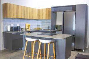 a kitchen with a counter with stools and a refrigerator at 12 Elizabeth Place - Luxury Apartments, Free Wi-Fi in Midrand