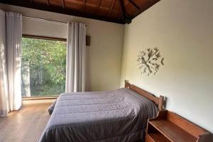 a bedroom with a bed and a large window at Chalé Canto da Montanha in Serra do Cipo