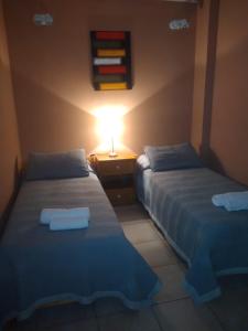 two beds in a room with a lamp on a table at Departamentos la Merced in San Nicolás de los Arroyos