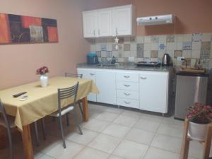 a kitchen with a table and white cabinets and a table and chairs at Departamentos la Merced in San Nicolás de los Arroyos