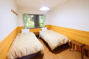 two beds in a room with a window at Village Kagetsuen in Yamanakako