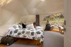 a woman laying on a bed in a tent at Stay Wilder Sunshine Coast in Sechelt