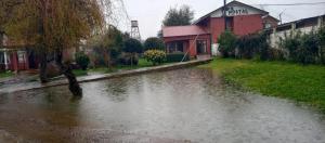 a flooded street with a river in front of a building at Hostal Rama Fueguina in Teodoro Schmidt