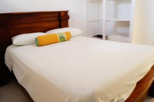 uma cama branca com uma almofada amarela em Casita Marlín Quepos em Quepos