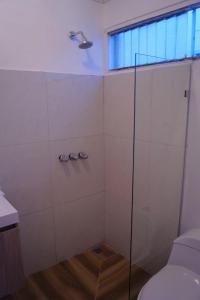 uma casa de banho com um chuveiro, um WC e uma janela. em Casita Marlín Quepos em Quepos