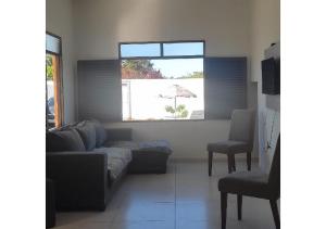 ein Wohnzimmer mit einem Sofa, einem Stuhl und einem Sonnenschirm in der Unterkunft Hostel Summer Praia do Sol in João Pessoa