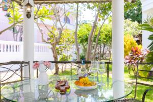 a glass table with a bowl of fruit and glasses on it at Ruby Villa in Vung Tau
