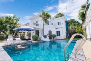 a swimming pool in front of a white house at Ruby Villa in Vung Tau