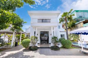 an exterior view of a white house with trees at Ruby Villa in Vung Tau
