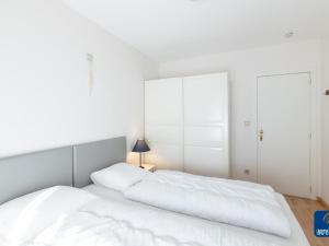 a white bedroom with a large bed with white sheets at Apartment on Belgian Coast with Sea View in De Haan