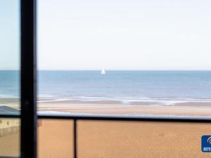 a view of a beach with a sailboat in the ocean at Apartment on Belgian Coast with Sea View in De Haan