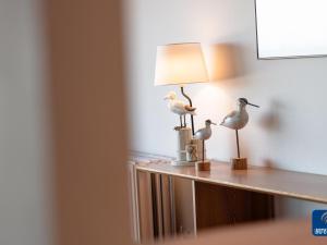 two birds sitting on a table next to a lamp at Apartment on Belgian Coast with Sea View in De Haan