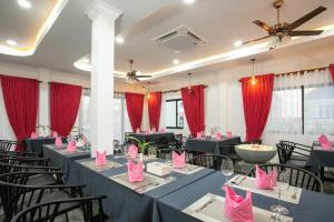 Cambana Poipet Hotel في بويبيت: قاعة احتفالات مع طاولات وكراسي بمناديل وردية