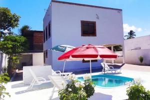 eine Terrasse mit einem roten Sonnenschirm und Stühlen sowie einem Pool in der Unterkunft Hostel Summer Praia do Sol in João Pessoa